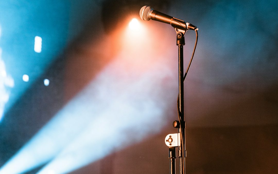 Microphone stand lit by blue and amber stage lights, symbolizing easy open mic signup and stage time booking on OnlineOpenMic.com